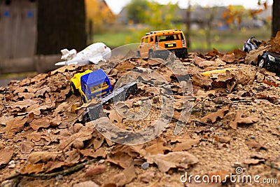 Forgotten children`s toys on a pile of sand under the autumn foliage Stock Photo