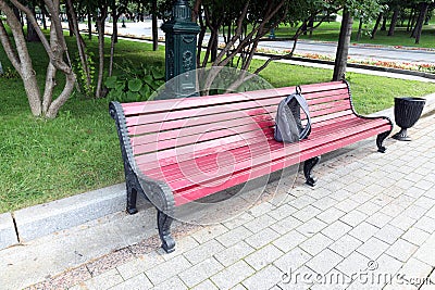 Forgotten gray backpack on a red bench in the park Stock Photo
