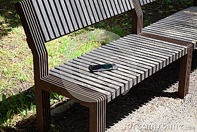 Forgotten smartphone on the wooden bench in the city park. lost phone in the park. Stock Photo