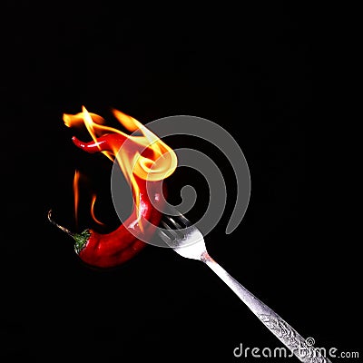 Fork impale to red hot chili on black Stock Photo