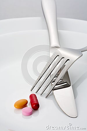 Fork, knife and three pills on a plate Stock Photo