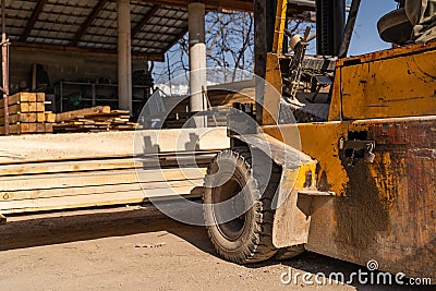 Fork lifter at warehouse lifting timber planks in sunny day no people Stock Photo