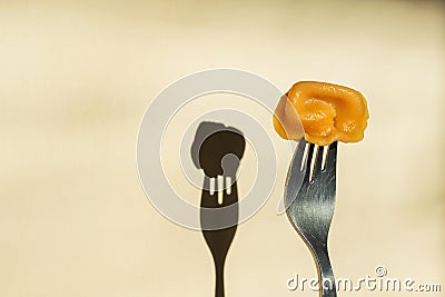 Fork with orange color dumplings on the background of a wall with a shadow Stock Photo
