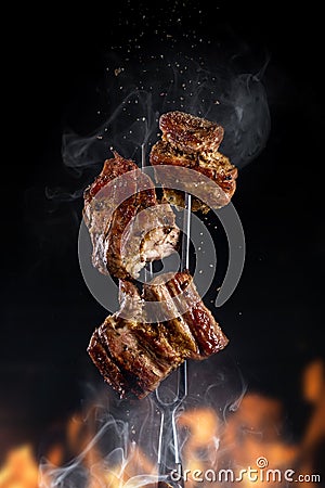 Fork with pieces of delicious barbecued meat on black background Stock Photo