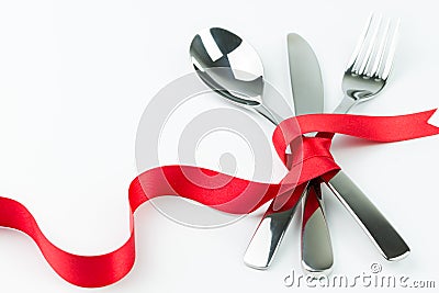 Fork, spoon and knife tied up with red ribbon Stock Photo