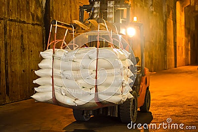 Forklift carries jumbo bag of refine white sugar to put on the stack inside warehouse. Sugar warehouse operations and management. Stock Photo