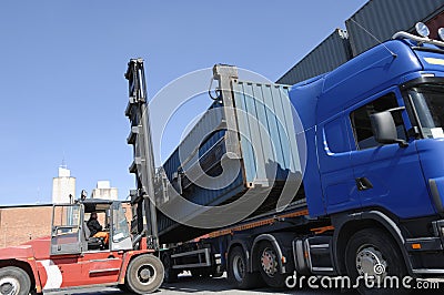 Forklift hoisting cargo and shipping containers Stock Photo