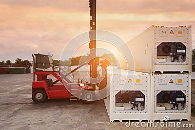 Forklift reach stacker is lifting reefer container in the depot. Stock Photo