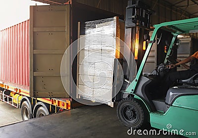 Forklift Tractor Loading Packaging Boxes into Shipping Container. Trucks Loading Dock Warehouse. Delivery Cargo Trucks Logistics Stock Photo