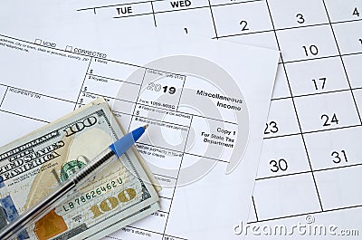 Form 1099-misc Miscellaneous income and blue pen with dollar bills lies on office calendar. Internal revenue service tax form Stock Photo