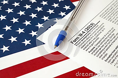 Form W-4 Employee`s withholding allowance certificate instructions and blue pen on United States flag. Internal revenue service Editorial Stock Photo