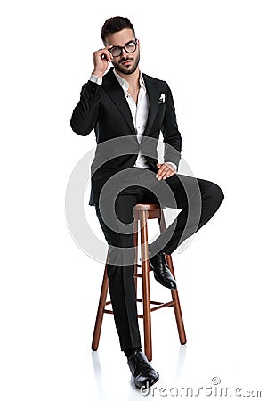 Formal business man sitting and fixing glasses Stock Photo