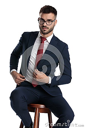 Formal man sitting and fixing jacket with style Stock Photo