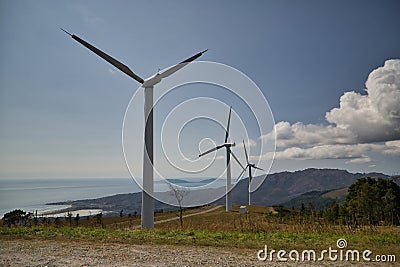 Formation of several wind turbines placed on a mountain facing the ocean. Concept renewable energy, electricity, environment, Stock Photo