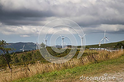 Formation of several wind turbines placed on a mountain on a very cloudy day. Concept renewable energy, electricity, environment, Stock Photo