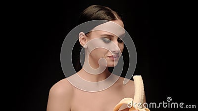 Forme a posição moreno no fundo preto da parede no estúdio, comendo uma banana video estoque Forme a posição moreno no fundo preto da parede no estúdio, comendo uma banana video estoque