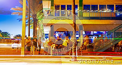 FORT LAUDERDALE, FL - FEBRUARY 2016: People enjoy night life at local pubs, traffic on the foreground Editorial Stock Photo