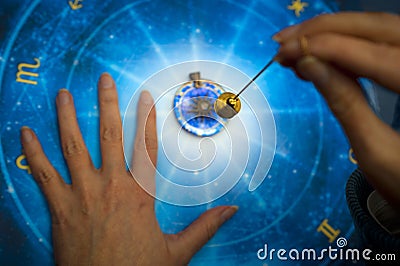 Fortune teller with magic pendulum on blue horoscope like astrology, zodiac. esoteric topic Stock Photo