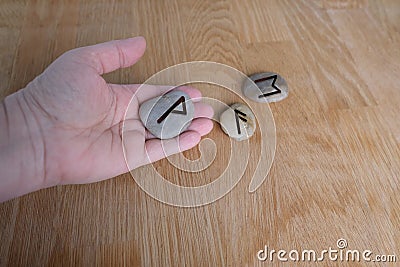 Fortuneteller`s hand explains the meaning of the Scandinavian, Slavic runes on flat stones for fortune-telling for the future, th Stock Photo