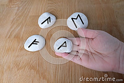 Fortuneteller`s hand explains the meaning of the Scandinavian, Slavic runes on flat stones for fortune-telling for the future, th Stock Photo