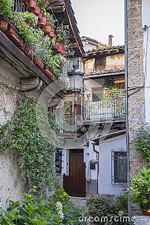 FotografÃ­a vertical de una estrecha calle peatonal adornada con macetas y plantas en la villa de Candelario, EspaÃ±a Editorial Stock Photo