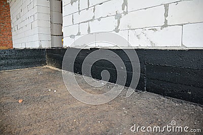 Foundation bitumen waterproofing. Building house construction with waterproofing spray-on tar. Construction techniques for Stock Photo