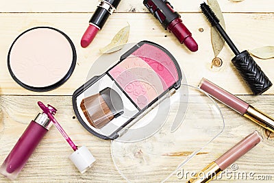 foundation powder and three color blush, variety lipstick and lip gloss, mascara brush on wood table. Stock Photo