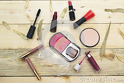 Foundation powder and three color blush, variety lipstick and lip gloss, mascara brush on wood table. Stock Photo