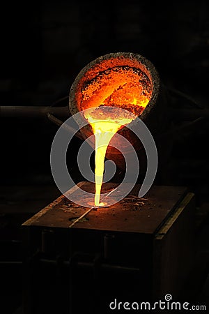 Foundry - molten metal poured from ladle into moul Stock Photo