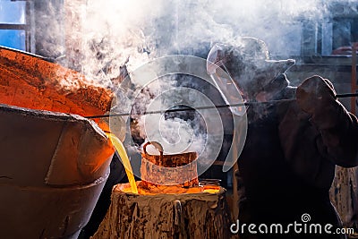 Foundry worker in a protective mask looks inside the vat in which the molten metal Stock Photo