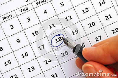 Fountain pen in woman hand marking day on calendar Stock Photo