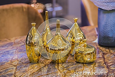 Four beautiful glossy golden vases. Gold fashionable glass vases on a marble table. Stylish luxirious interior element Stock Photo