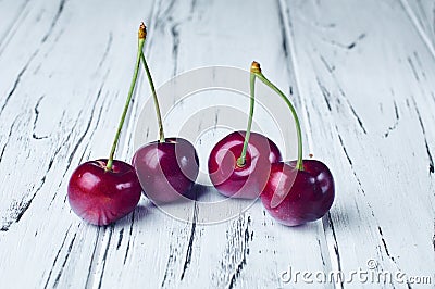 Four beautiful red cherries on a white wooden table Stock Photo