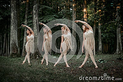Four beautiful slender young female dancers dance synchronously in the forest. Stock Photo