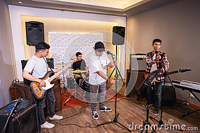 four boys checking musical instruments before starting to practice Stock Photo