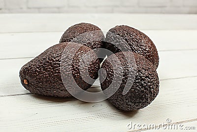 Four brown whole avocados on white boards Stock Photo