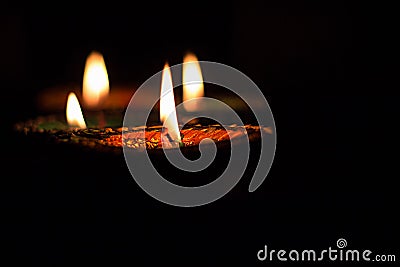 Four burning colorful candles indian style for Diwali celebration on black background. Vertical Stock Photo