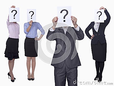 Four business people holding up paper with question mark, obscured face, studio shot Stock Photo