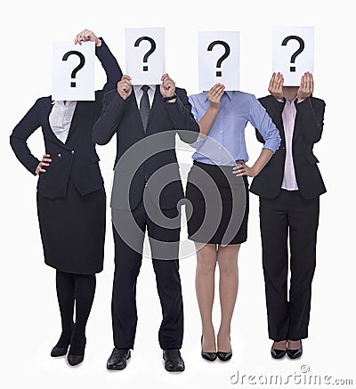 Four business people holding up paper with question mark, obscured face, studio shot Stock Photo