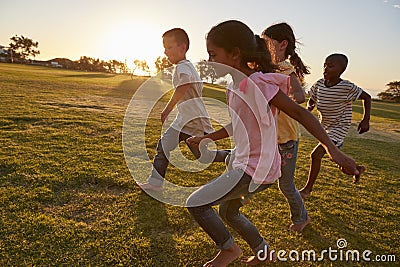 Four children running barefoot in a park Stock Photo