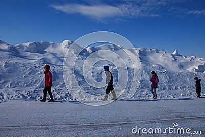 Four Children Walking next to a Tall Snow Drift Stock Photo