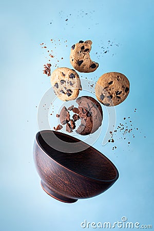 Four chocolate chip cookies and a bowl flying on a blue background Stock Photo
