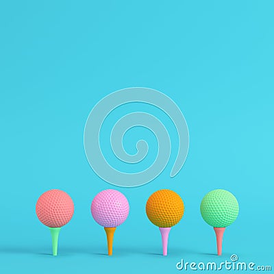 Four colorful golf balls with tee on bright blue background in pastel colors. Minimalism concept Stock Photo