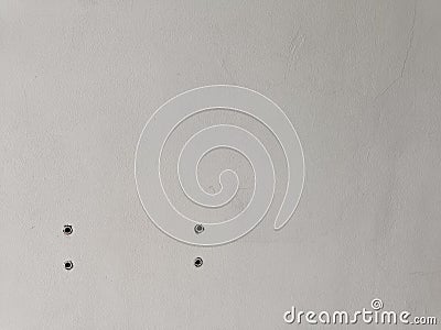 Four cracks holes on the white cement wall caused by drilling for cable installation. Wall Hole for electricity Stock Photo
