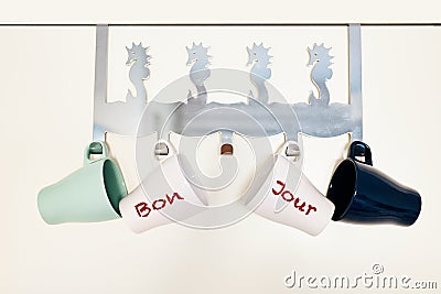 Four cups hanging on a door coat rack with bonjour word in french Stock Photo