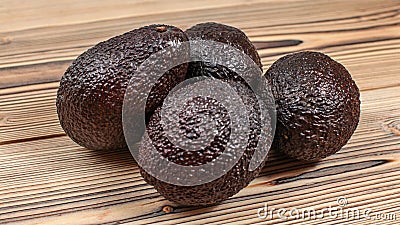 Four dark brown ripe avocados on wooden boards table Stock Photo