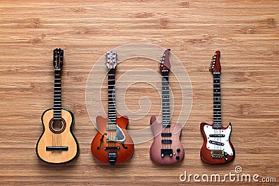 Four different electric and acoustic guitars on a wooden background. Toy guitars. Music concept. Stock Photo