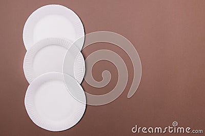 Four eco-friendly white paper plates lie on brown background with copy space. top view. close-up Stock Photo