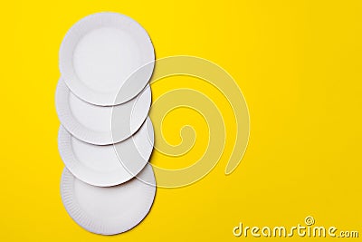 Four eco-friendly white paper plates lie on yellow background with copy space. top view. close-up Stock Photo