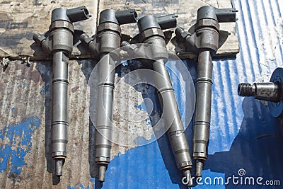 Four fuel injectors are lying on a blue work table in an auto repair shop Stock Photo